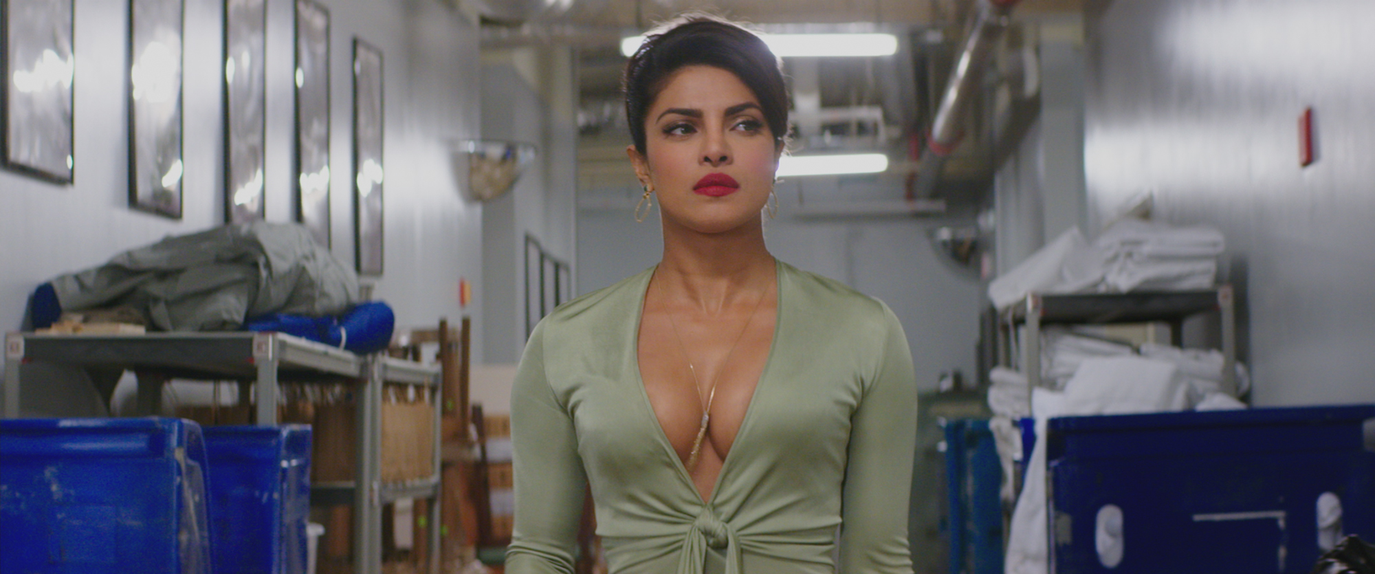 Priyanka Chopra in a revealing green dress at a party in Baywatch, highlighting the "sexy agent" trope for women of color.